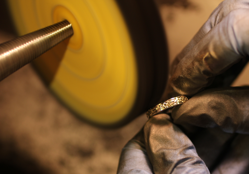 Depicted here is one of our gold wedding bands, the Trinity Twist Wedding Ring, being polished on a polishing wheel.